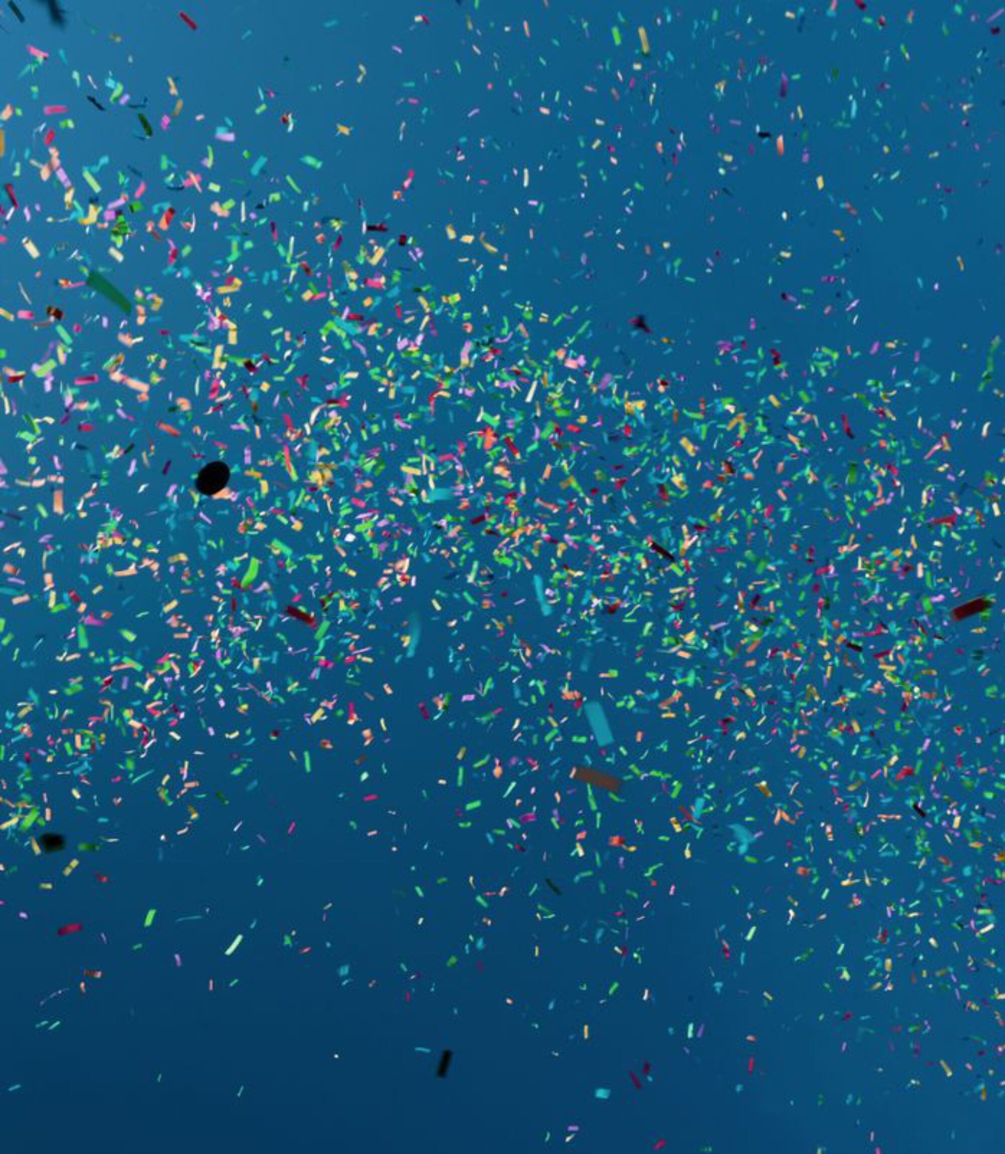 Small festive pieces of paper of various colors falling down against blue water