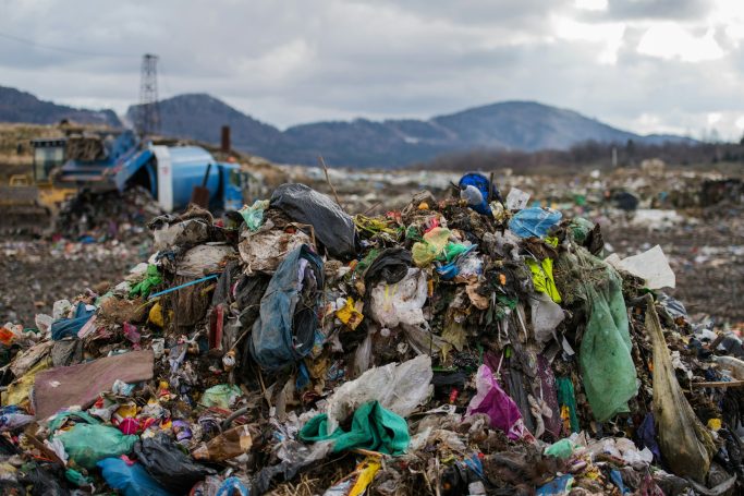 Mikroplastik Haufen von Müll und Plastikabfällen vor einer hügeligen Landschaft.